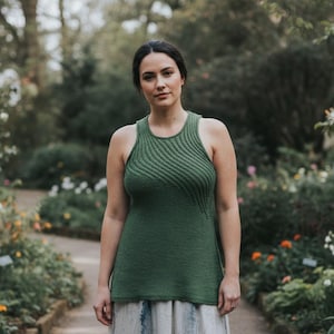 以下が含まれることがあります： 胸と肩にテクスチャ加工された斜め模様が入ったグリーンのタンクトップ。ノースリーブで丸いネックラインです。庭園の中に立っており、小道と花があります。