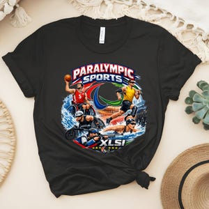 May include: Black t-shirt featuring a colorful graphic of Paralympic athletes in action, including basketball, running, swimming, and shooting. The design includes the words "PARALYMPIC SPORTS" and "XLSI" in a dynamic, sporty style.