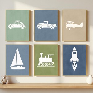 May include: Six framed art prints with white vehicle illustrations: a car, truck, aeroplane, sailboat, train, and rocket. They are set against coloured backgrounds and displayed on a wooden shelf with a teddy bear and a vase.