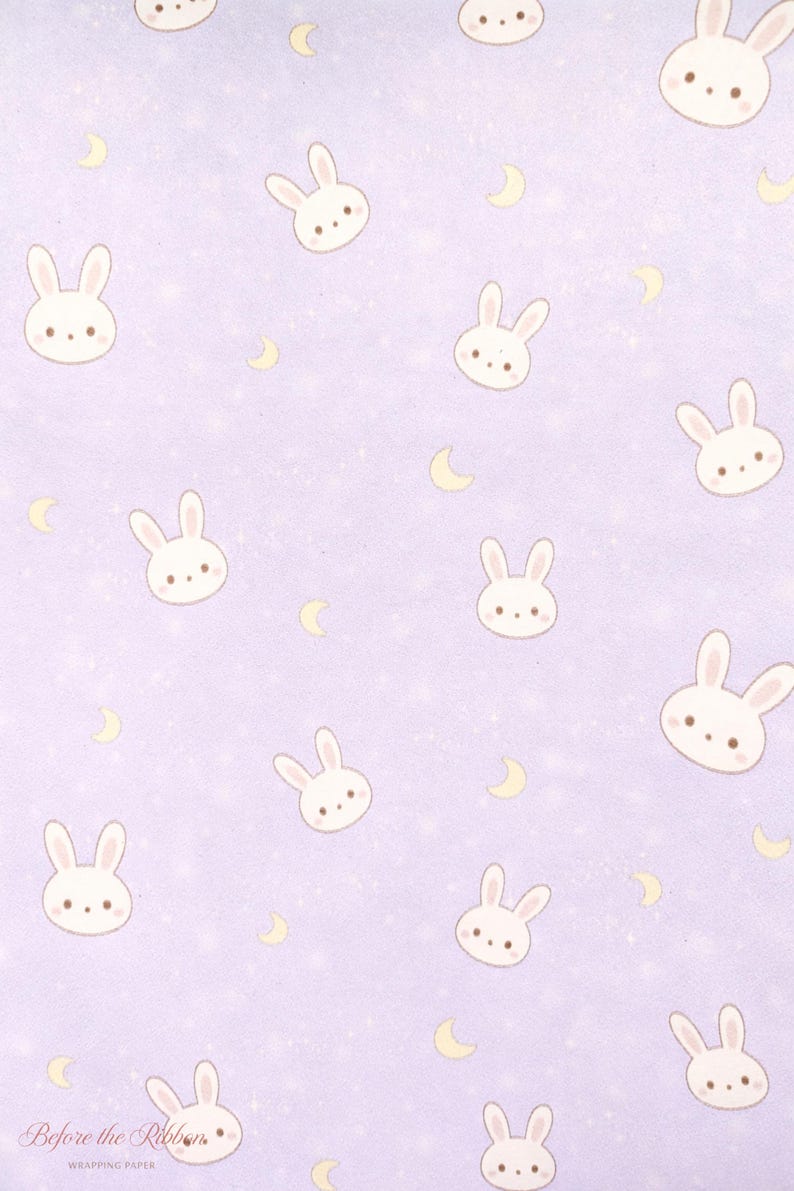 May include: Lavender wrapping paper with a repeating pattern of white bunny faces, yellow crescent moons, and small white stars. The words "Before the Ribbon" are printed in a script font at the bottom left.