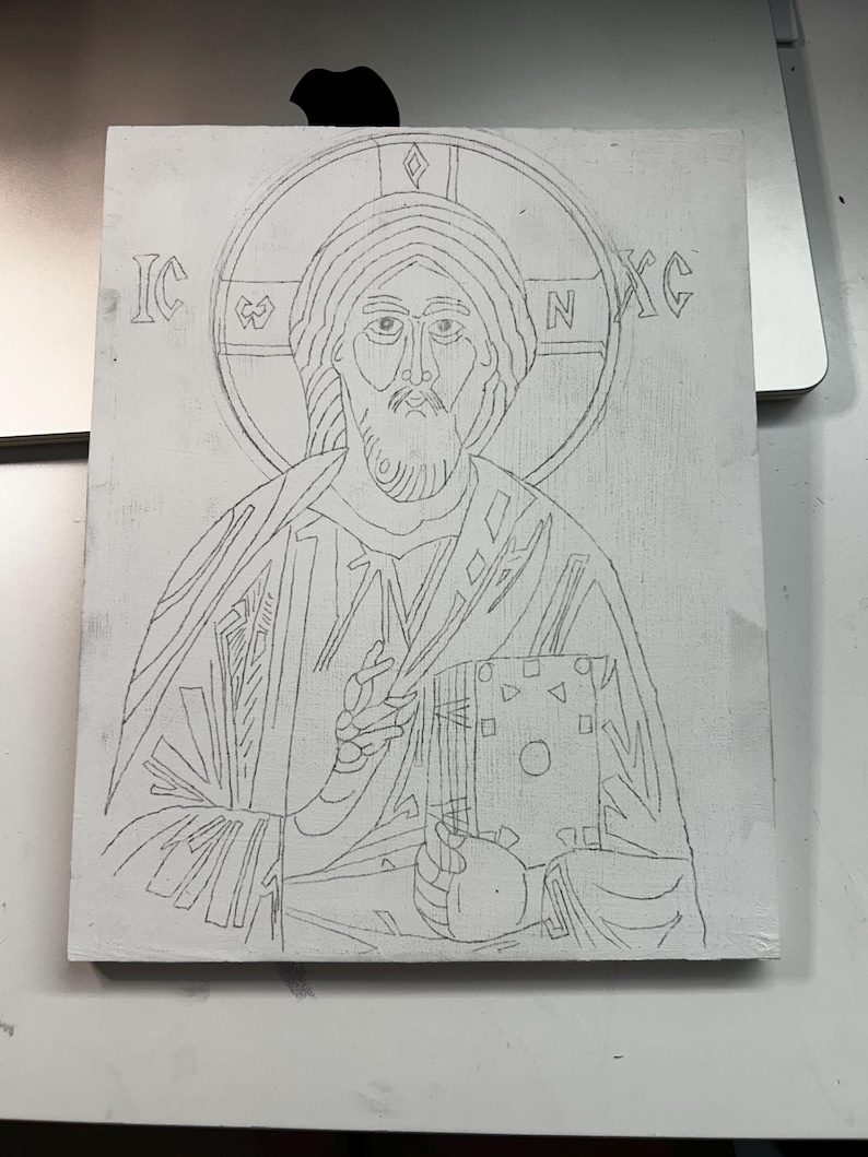Pu&ograve; includere: Un pannello rettangolare bianco con un disegno a matita di grafite raffigurante una figura con un'aureola che tiene in mano un libro. Le lettere IC e XC sono visibili su entrambi i lati dell'aureola. Il disegno mostra una persona barbuta.