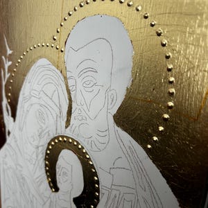 Pu&ograve; includere: Un pannello icona religiosa con sfondo in foglia d'oro e un design a aureola con punti in rilievo. L'opera mostra un disegno a linee di tre figure in stile tradizionale, con una piccola aureola centrale riempita di foglia d'oro e punti.
