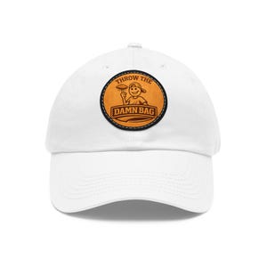 May include: A white baseball cap featuring a circular tan leather-like patch on the front. The patch displays a cartoon character wearing a cap and holding a bag, with the text THROW THE DAMN BAG printed in bold, dark brown capital letters.