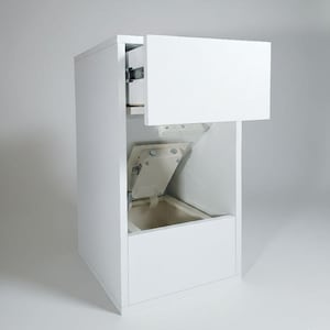 Puede incluir: Un armario blanco con un cajón abierto y una puerta con bisagras que revela un compartimento interior. El armario es rectangular y parece estar hecho de madera o un material similar. El cajón está parcialmente extendido, mostrando su interior. La puerta está abierta, revelando el interior.