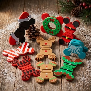 May include: A collection of nine holiday-themed plastic clips featuring various designs including a Santa hat, a green wreath, a red suit with a belt, a candy cane stripe, a reindeer, a snowflake, a red and black pattern, a gingerbread man, and an elf suit.