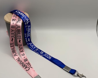 May include: A pink lanyard and a blue lanyard, each featuring the printed text "CARNIVAL JUBILEE ~ JULY 11 - 18, 2026". Both lanyards are made of fabric, include a silver-toned metal crimp, and terminate in a silver-toned metal lobster claw clasp.