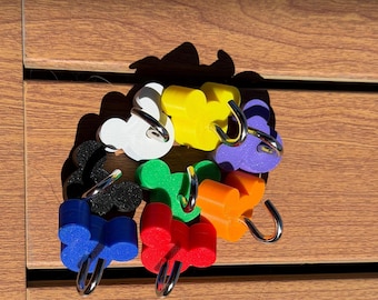 May include: A collection of seven colorful hooks, each featuring a mouse-ear silhouette design. The hooks are available in white, yellow, purple, orange, red, blue, green, and black, with each piece including a curved silver metal hook attachment.