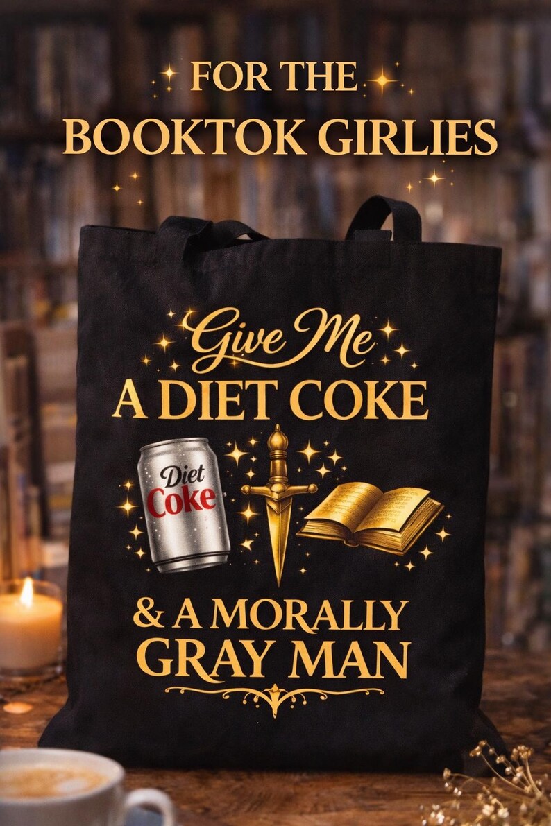 May include: Black tote bag with the text "FOR THE BOOKTOK GIRLIES" and "Give Me A DIET COKE & A MORALLY GRAY MAN." The design includes a Diet Coke can, a sword, and a book.