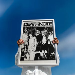 May include: A framed black and white Death Note poster held against a bright blue sky. The poster features manga-style illustrations of characters and the title "DEATH NOTE" in bold lettering, with the author's name below.
