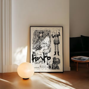 May include: A framed black and white comic book style poster with Japanese text and illustrations. A round, white globe lamp sits on the floor in front of the poster. The poster is leaning against a white wall.