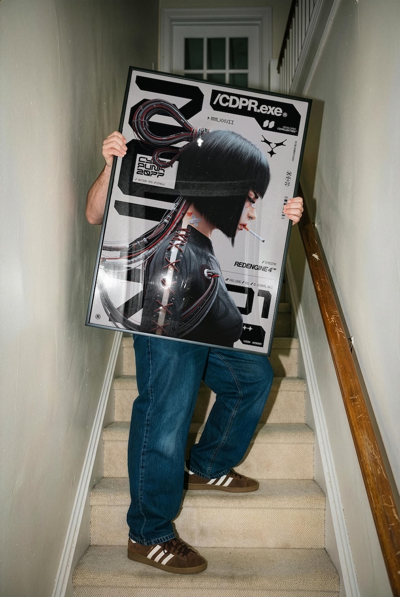 Op de afbeelding: Een ingelijste poster met een futuristische vrouw met zwart haar en een sigaret, tegen een zilveren en zwarte achtergrond. De poster bevat de tekst "/CDPR.exe" en "Cyberpunk 2077". De persoon draagt een blauwe spijkerbroek en bruine sneakers.