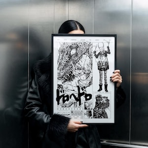 May include: A framed black and white artwork with manga illustrations and Japanese text. The artwork, titled "Dorohedoro", is held in front of a person. The frame is black. The artwork is displayed in a lift.
