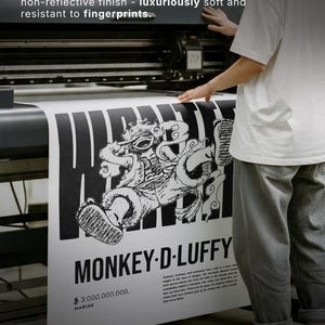 Op de afbeelding: Zwart-wit poster met de tekst "MONKEY-D-LUFFY" en "$3.000.000.000. MARINE". De poster is gedrukt op premium mat papier, 200 g/m&sup2;. De poster toont een gedetailleerde illustratie van een personage.