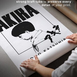 Może przedstawiać: Czarno-biały plakat z napisem "AKIRA" dużymi literami. Plakat jest zwijany, widoczny jest tekst "DESIGNED TO TRAVEL SAFELY". Jest zwinięty i zapieczętowany w tubie z papieru kraft.