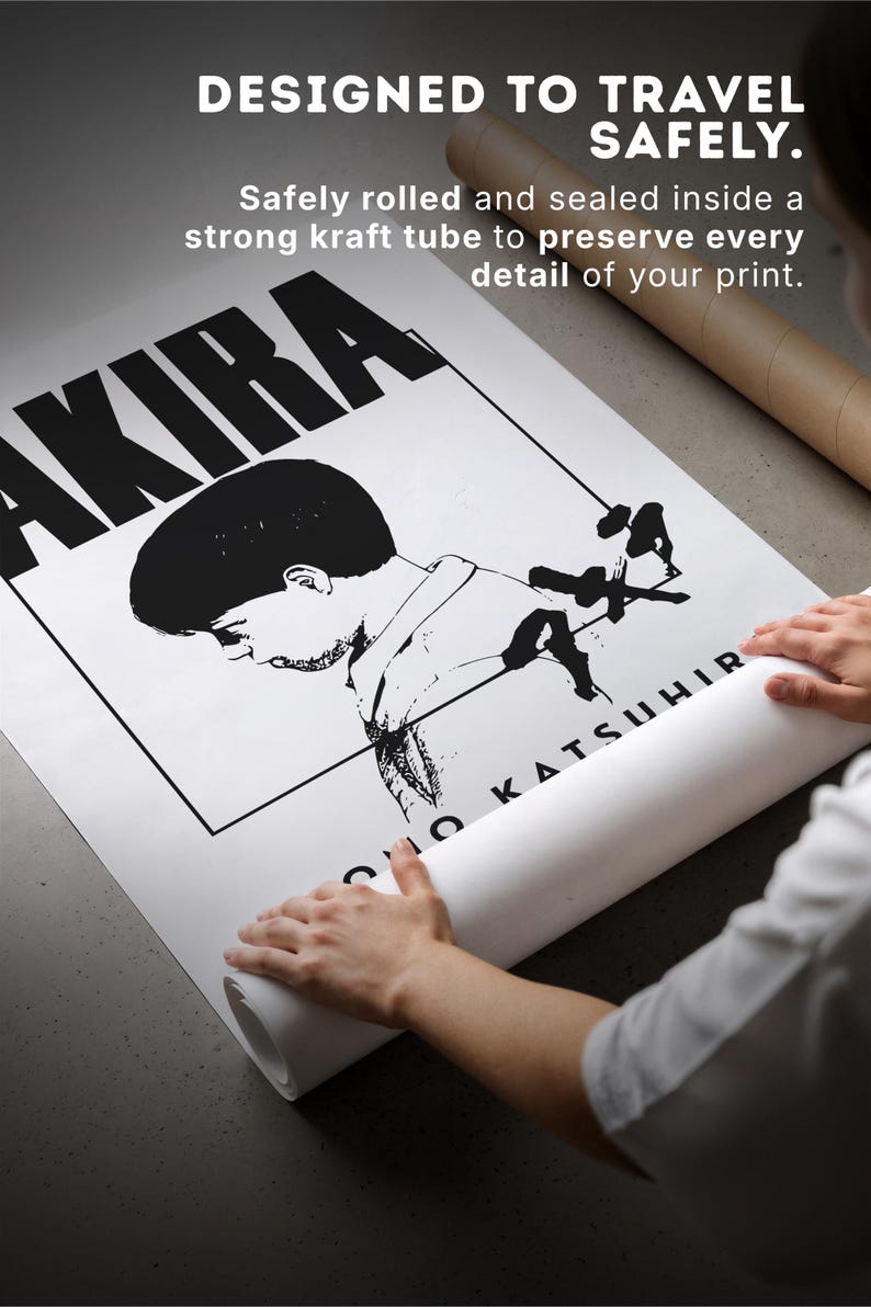 Op de afbeelding: Zwart-wit poster met het woord "AKIRA" in grote letters. De poster wordt opgerold, met de tekst "DESIGNED TO TRAVEL SAFELY" zichtbaar. Het is opgerold en verzegeld in een kraftkoker.