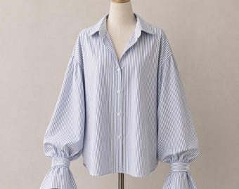 Camicetta oversize a righe con maniche a sbuffo e polsini svasati, chiusura con bottoni.