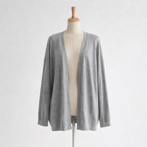May include: A grey cardigan, with long sleeves, displayed on a mannequin. The open front and soft knit fabric create a relaxed shape. This versatile garment is suitable for layering and adds a touch of casual elegance to any outfit. The cardigan is approximately 100 cm in length.