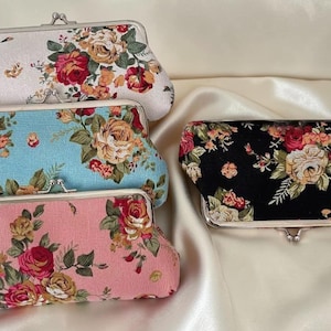 Puede incluir: Cuatro bolsos de mano con estampado floral en blanco, azul claro, rosa y negro. Cada bolso tiene un cierre plateado y un patrón repetido de rosas y otras flores en tonos rojos, naranjas y amarillos.