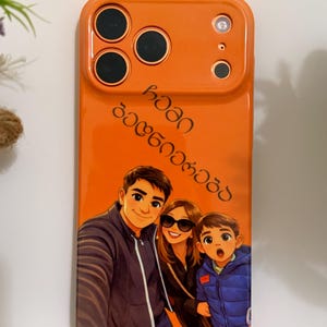 Puede incluir: Funda de teléfono naranja brillante con un retrato familiar de dibujos animados. La funda tiene recortes para la cámara y el flash del teléfono. La ilustración muestra a un hombre, una mujer con gafas de sol y un niño. La funda también tiene texto en idioma extranjero.