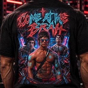 Könnte beinhalten: Ein schwarzes T-Shirt mit einem großen Grafikdruck auf der Rückseite. Das Design zeigt den Text "COME AT ME BRAH" in einer stilisierten roten und blauen Schrift über einer Illustration einer muskulösen Figur mit Sonnenbrille.