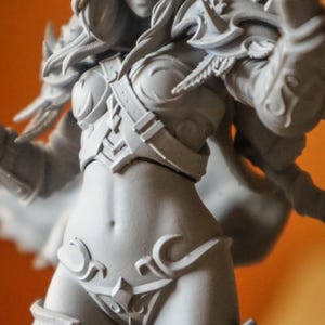 May include: An unpainted figurine of a female fantasy character, featuring detailed armour and a hooded cloak. The figure is posed with a bow and arrow, showcasing intricate design elements. The overall style is reminiscent of a video game character, with a focus on detailed craftsmanship.