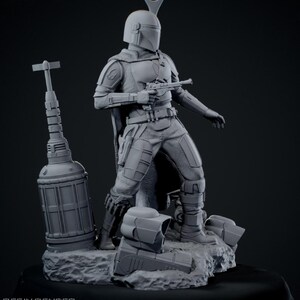 May include: A gray resin render of a Mandalorian figure, holding a blaster pistol. The figure is in a dynamic pose, standing on a rocky base with additional helmet pieces. The image includes text indicating it is 1/6th scale and lists 23 STL parts.
