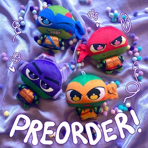 May include: Four plush Teenage Mutant Ninja Turtles toys in blue, red, purple, and orange. Each turtle has a distinctive mask and shell design. The word "PREORDER!" is written in a white, stylised font across the bottom of the image.