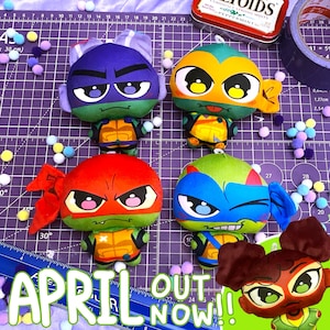 May include: Four plush turtle characters with large eyes and colorful masks in purple, orange, red, and blue, each wearing a brown and yellow shell. A fifth character with brown hair buns is partially visible in the corner. The background is a purple grid.