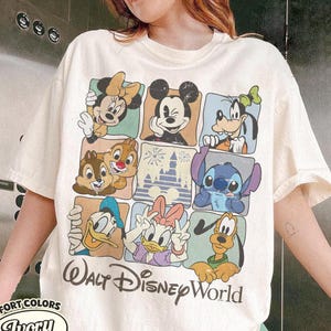 May include: Ivory-colored t-shirt featuring a grid of Disney characters including Mickey Mouse, Minnie Mouse, Goofy, Donald Duck, Daisy Duck, Chip and Dale, Stitch, and Pluto. The words "Walt Disney World" are printed below the grid.
