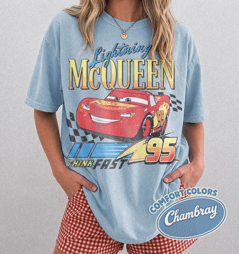 K&ouml;nnte beinhalten: Hellblaues T-Shirt mit einem Lightning McQueen-Motiv aus dem Film Cars. Die Grafik zeigt den Schriftzug "Lightning McQueen", die Nummer "95" und den Satz "Think Fast". Das T-Shirt hat einen Vintage-Look.