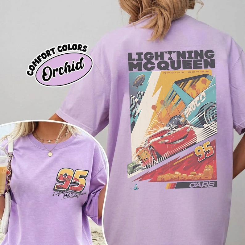 May include: A light purple t-shirt featuring a graphic of Lightning McQueen from the Cars movie. The design includes the number 95, the text "Lightning McQueen Racing Series", and a racing scene. The shirt also has the text "Comfort Colors Orchid".