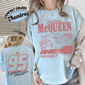 May include: Light blue t-shirt featuring Lightning McQueen graphic with the number 95 and the text "Think Fast". The back of the shirt also displays the number 95 and "Lightning McQueen".