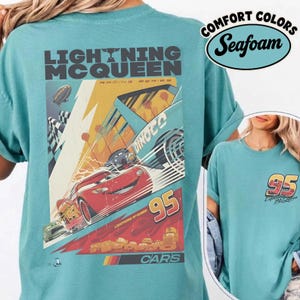 May include: Seafoam green t-shirt featuring a graphic of Lightning McQueen from the Cars movie. The design includes the number 95, the Dinoco logo, and the words "Lightning McQueen" and "Cars". The shirt also has the words "Comfort Colors" and "Seafoam".