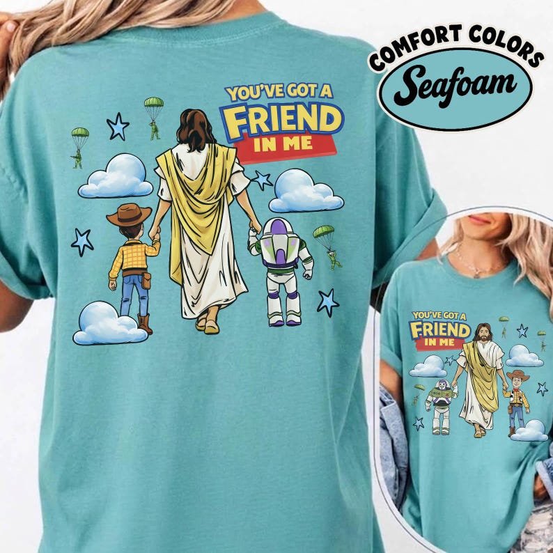May include: A seafoam green t-shirt with a graphic of Jesus holding hands with cartoon characters. The text "YOU'VE GOT A FRIEND IN ME" is above the figures. The shirt also has the words "COMFORT COLORS" and "Seafoam" printed on it.