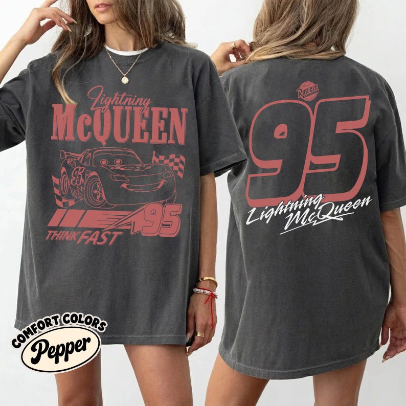 May include: Dark gray t-shirt featuring Lightning McQueen from the Cars movie. The front graphic includes the character's image, the text "Lightning McQueen," and "95." The back displays a large "95" and "Lightning McQueen" in white.