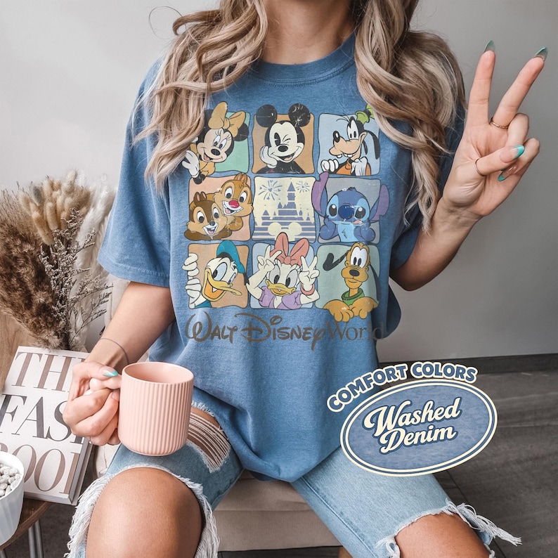May include: Blue Comfort Colors t-shirt featuring a grid of Disney characters including Mickey Mouse, Minnie Mouse, Donald Duck, and Goofy. The shirt has the text "Walt Disney World" and "Comfort Colors Washed Denim".