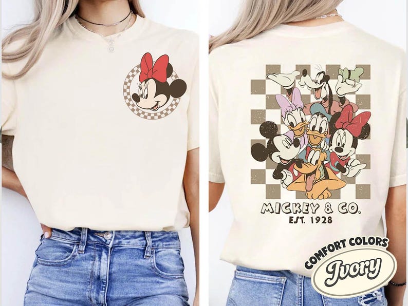 May include: Ivory-colored t-shirt featuring Minnie Mouse with a red bow on the front and a group of Disney characters on the back. The back design includes Mickey Mouse, Donald Duck, Goofy, and Daisy Duck. The shirt has the text "Mickey & Co. Est. 1928".