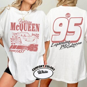 May include: White t-shirt featuring a red graphic of Lightning McQueen, the number 95, and the text "Think Fast." The back of the shirt displays a large number 95 and the words "Lightning McQueen."