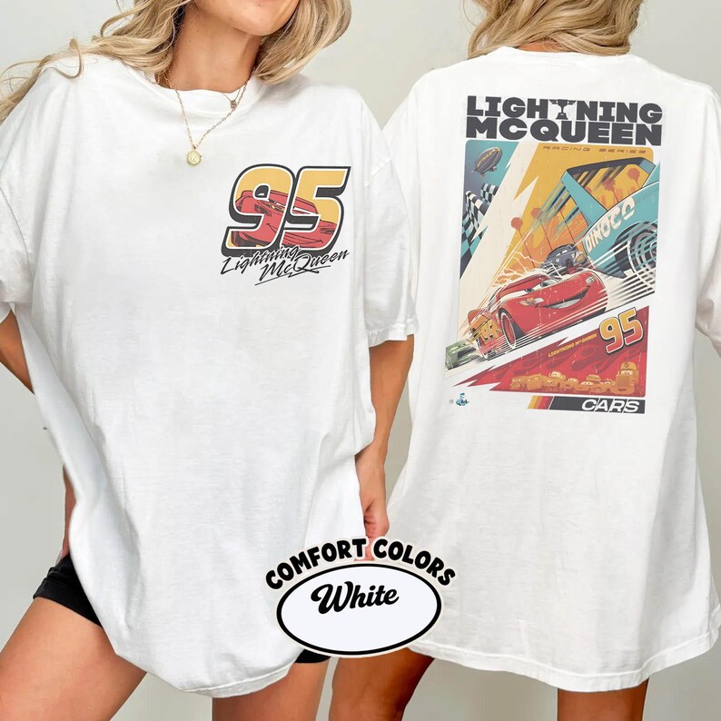May include: White t-shirt featuring Lightning McQueen from the Cars movie. The front displays "95" with "Lightning McQueen" text. The back showcases a racing scene with Lightning McQueen and the text "Lightning McQueen Racing Series".