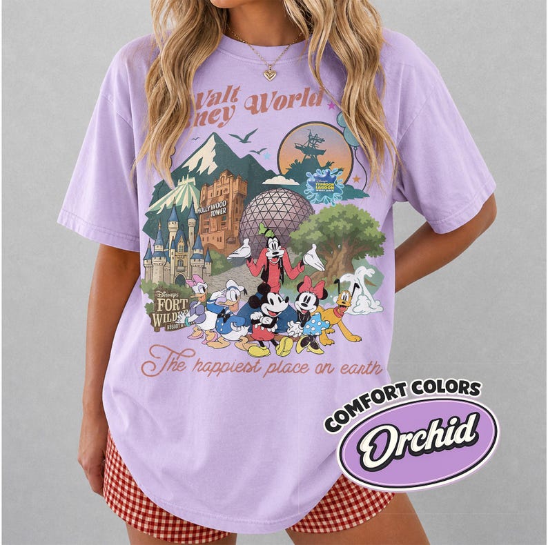 Pu&ograve; includere: Una maglietta lilla con una grafica colorata di personaggi e monumenti Disney. Il design include Topolino, Paperino e Pippo, con il testo "Walt Disney World" e "The happiest place on earth."