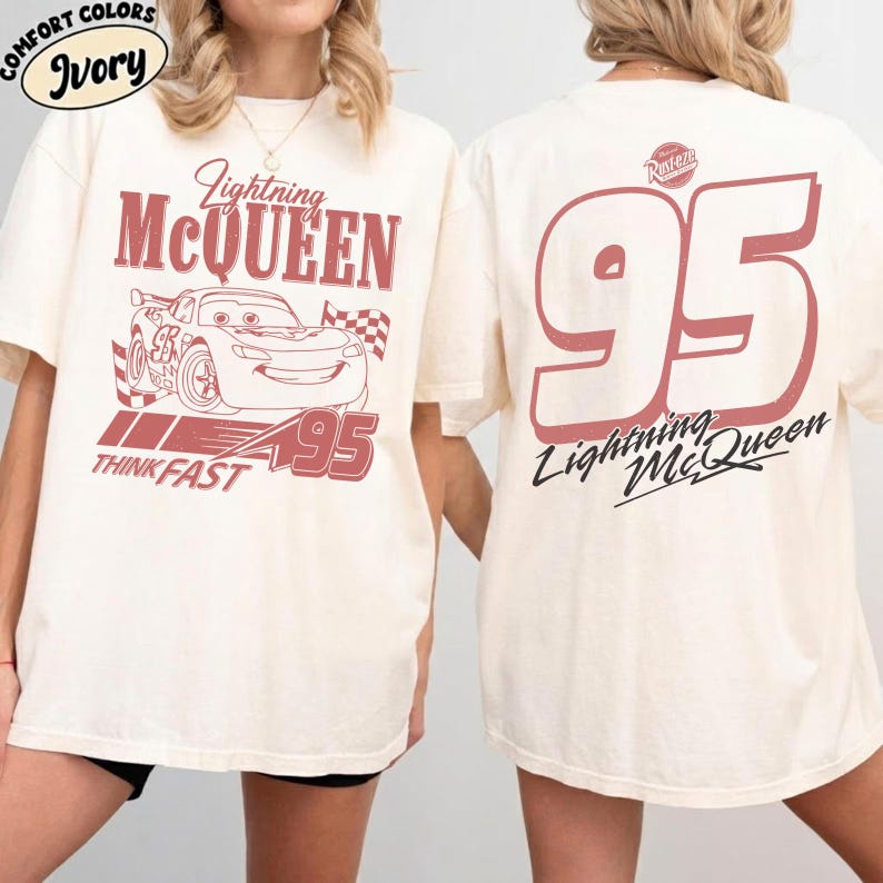 May include: Ivory-colored t-shirt featuring a Lightning McQueen design. The front graphic includes the text "Lightning McQueen", a cartoon car, the number "95", and the words "Think Fast". The back displays a large "95" and "Lightning McQueen" text.
