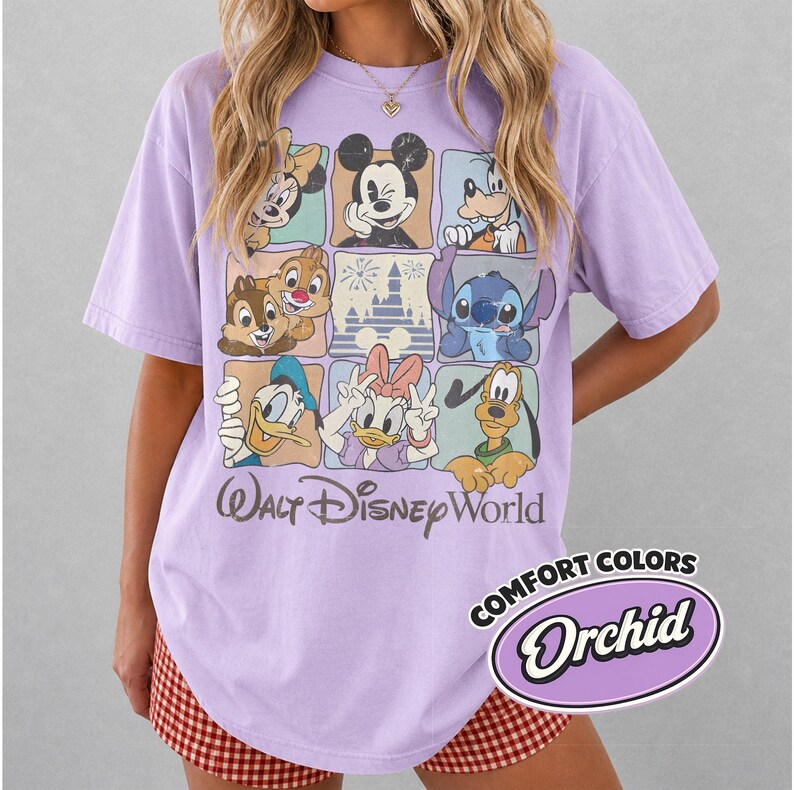May include: A lilac-colored t-shirt featuring a grid of Disney characters including Mickey Mouse, Minnie Mouse, Donald Duck, and Stitch. The words "Walt Disney World" are printed below the grid. The shirt also has the words "Comfort Colors" and "Orchid" printed on it.