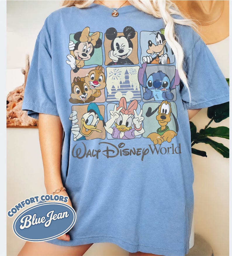 May include: Blue short-sleeve t-shirt featuring a grid of Disney characters including Mickey Mouse, Minnie Mouse, Donald Duck, and Stitch. The shirt has the words "Walt Disney World" printed on it. The shirt is labeled "Comfort Colors Blue Jean".