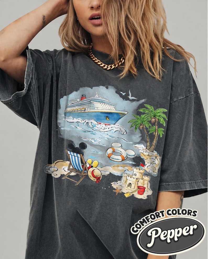 Op de afbeelding: Donkergrijze t-shirt met een kleurrijke strandsc&egrave;ne: cruiseschip, palmbomen, zandkasteel. De afbeelding bevat Mickey Mouse en de tekst "Comfort Colors Pepper".