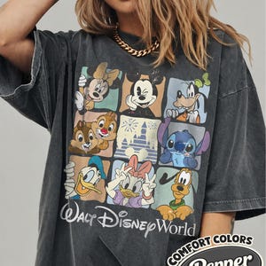 May include: Dark gray t-shirt featuring a colorful grid of Disney characters including Mickey Mouse, Minnie Mouse, and Goofy. The shirt has the words "Walt Disney World" in a script font. The shirt also has the words "COMFORT COLORS" and "Pepper".