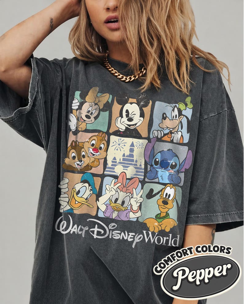 May include: Dark gray t-shirt featuring a colorful grid of Disney characters including Mickey Mouse, Minnie Mouse, and Goofy. The shirt has the words "Walt Disney World" in a script font. The shirt also has the words "COMFORT COLORS" and "Pepper".