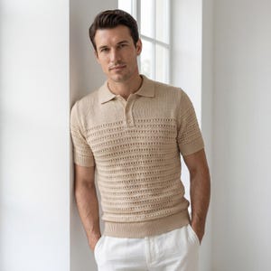 May include: A beige short-sleeved polo shirt with an open-knit design. The shirt has a classic collar and a three-button placket. The model is wearing white trousers. The shirt is made of a lightweight material. The shirt is a light tan colour.