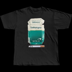 May include: Black t-shirt featuring a graphic of a crumpled Gothangelz Menthol Box and a cigarette. The box is white and teal with the brand name visible. The cigarette is white with a brown filter.