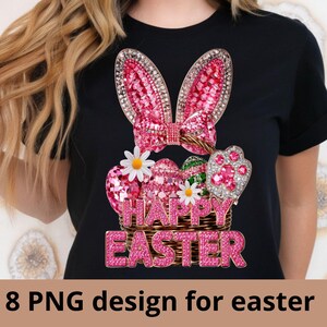 Könnte beinhalten: Schwarzes T-Shirt mit einem glitzernden Osterhasen-Design. Das Design umfasst rosa Ohren, eine Schleife und einen Korb voller dekorierter Eier. Die Worte "HAPPY EASTER" sind in rosa Glitzer dargestellt. Weiße Gänseblümchen fügen Details hinzu.