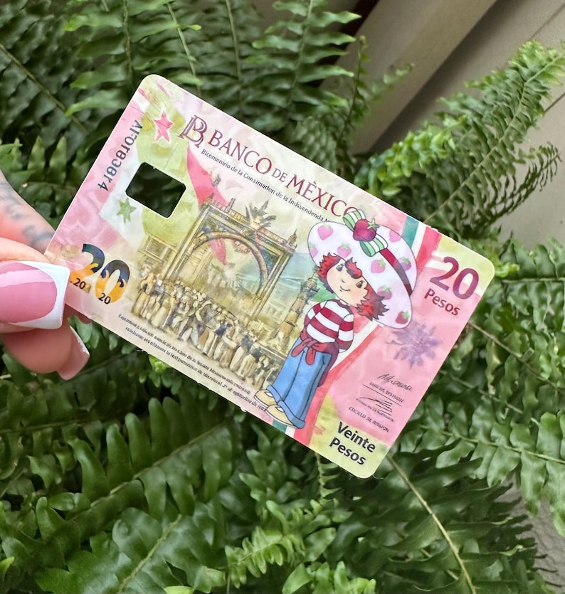 Może przedstawiać: Banknot dwudziestu pesos z Banco de M&eacute;xico z postacią z kresk&oacute;wki w kapeluszu truskawkowym. Banknot ma r&oacute;żowo-białą kolorystykę z napisem "Veinte Pesos".